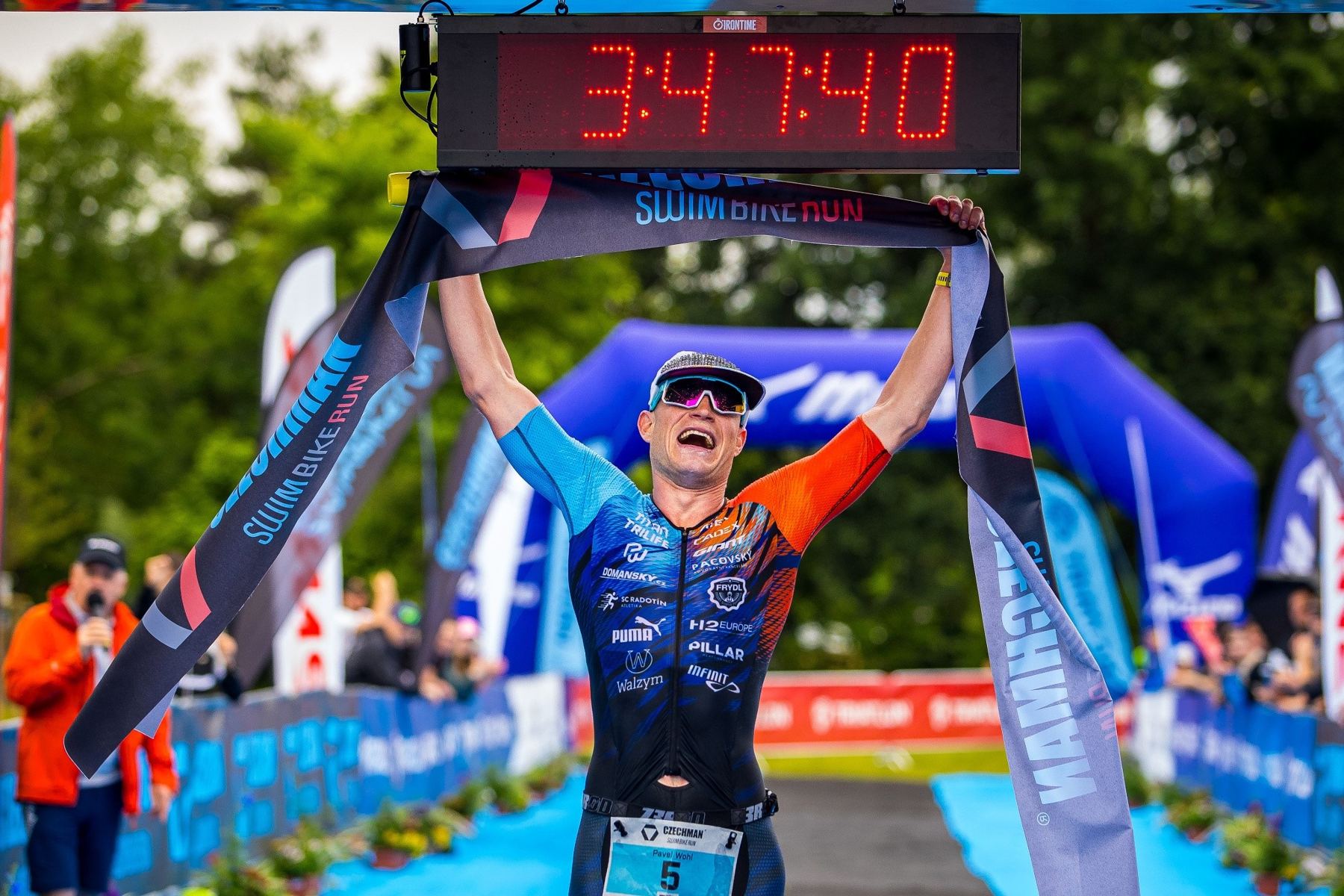 Pavel Wohl v cíli Czechmana s cílovou páskou nad hlavou, časomíra ukazuje 3:47:40